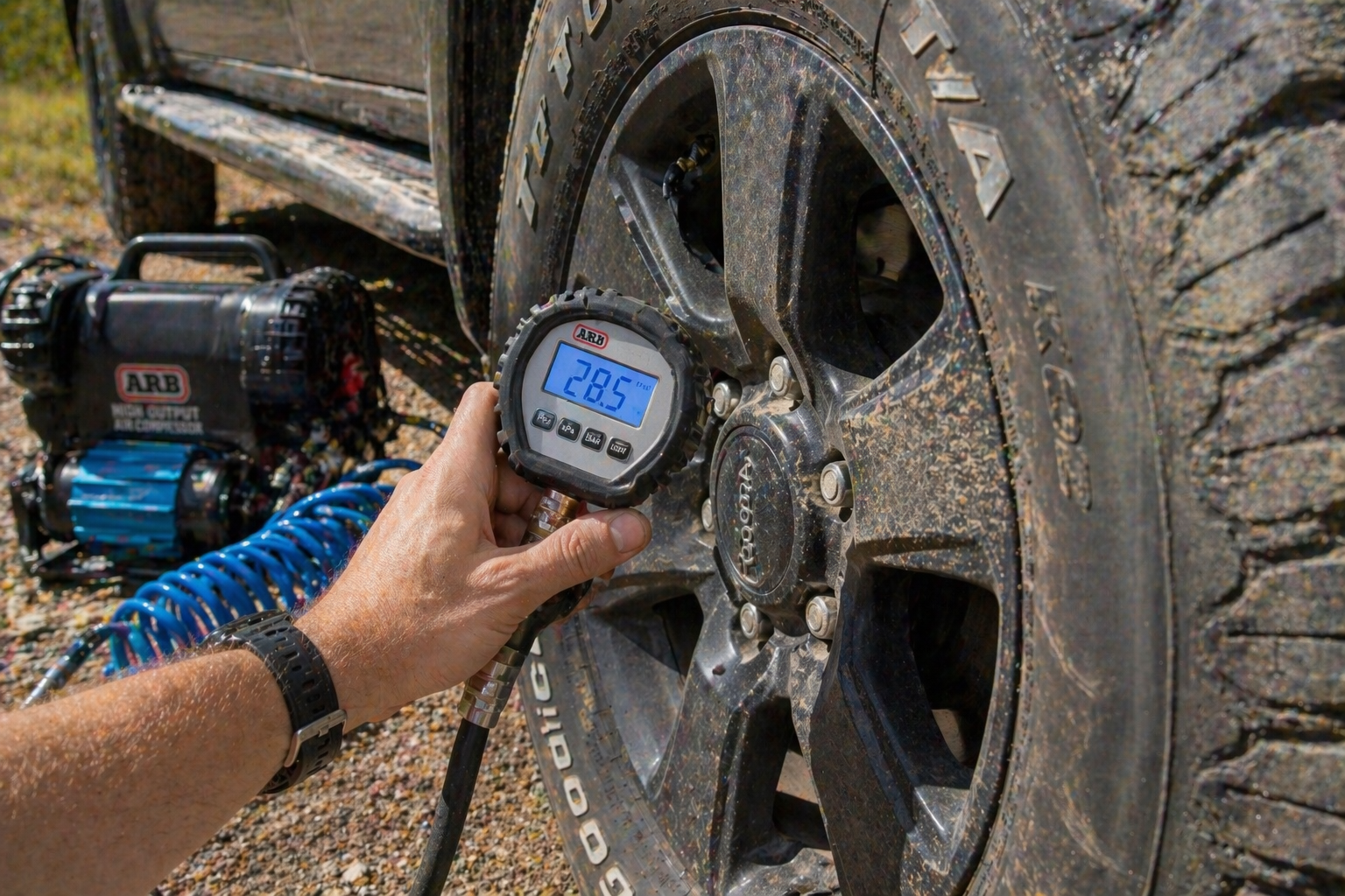 Close-up of a tyre pressure gauge on a 4WD tyre, ideally with a compressor visible.